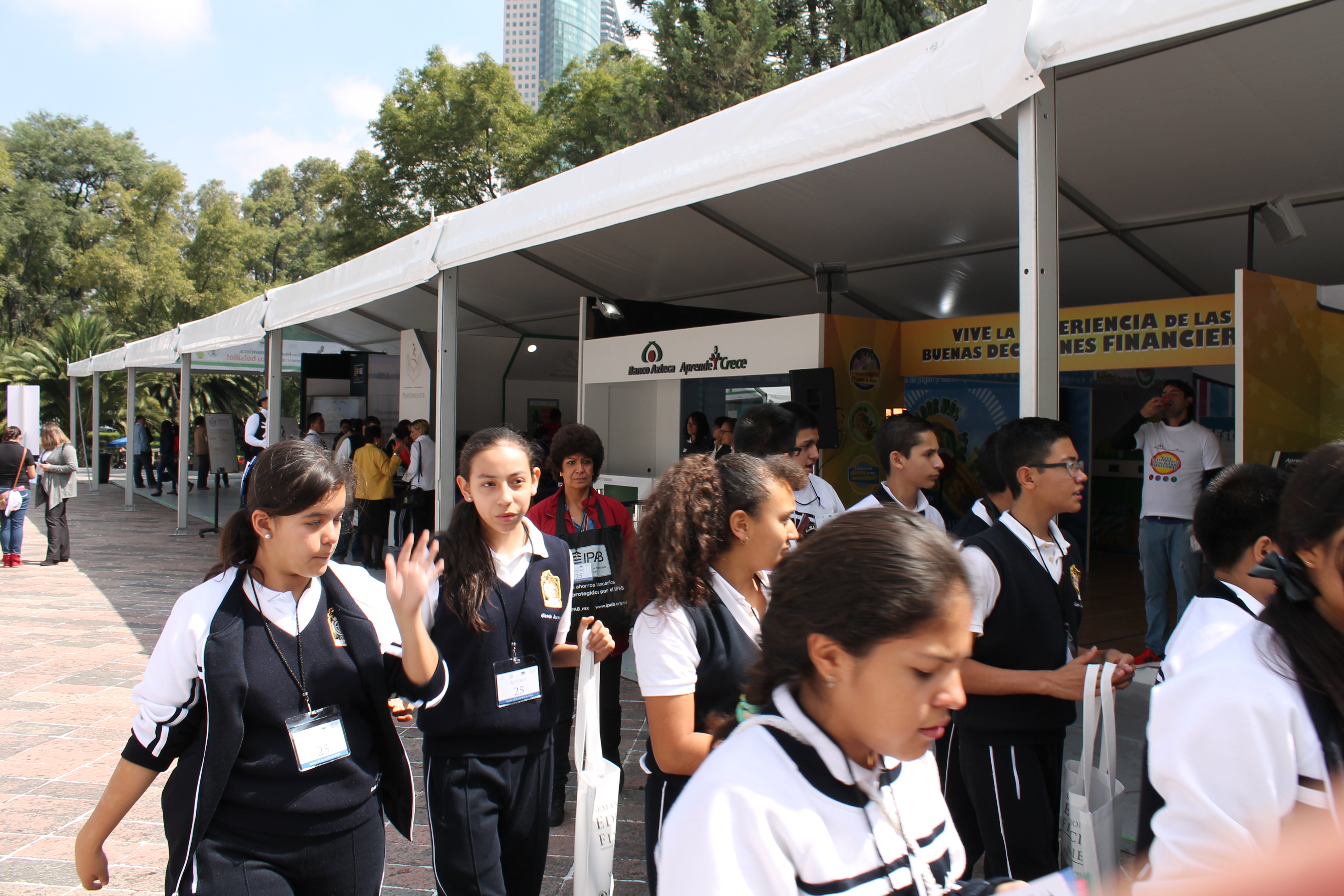 Niñas pasean frente al stand de Banco Azteca